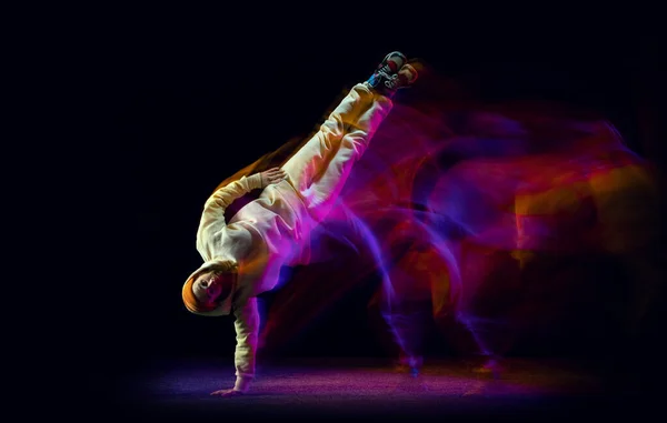 Solo dance. Mladý flexibilní sportovec tančící hip-hop nebo breakdance v bílém obleku na tmavém pozadí ve smíšeném žlutém neonovém světle. Krása, sport, mládež, akce, pohyby — Stock fotografie