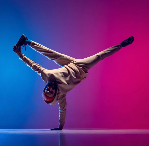 Estudio de un joven hombre deportivo flexible bailando breakdance en traje blanco sobre fondo azul rosado degradado. Concepto de acción, arte, belleza, deporte, juventud —  Fotos de Stock