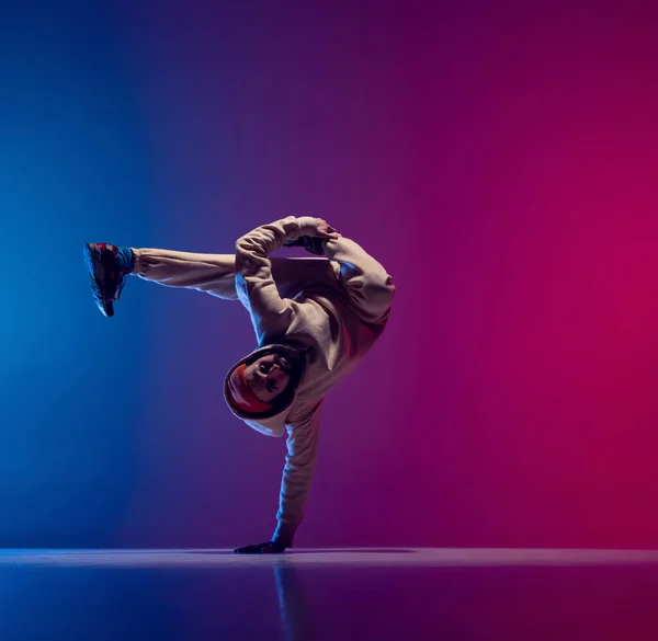 Estúdio tiro de jovem homem esportivo flexível dança breakdance em roupa branca em gradiente rosa fundo azul. Conceito de ação, arte, beleza, esporte, juventude — Fotografia de Stock