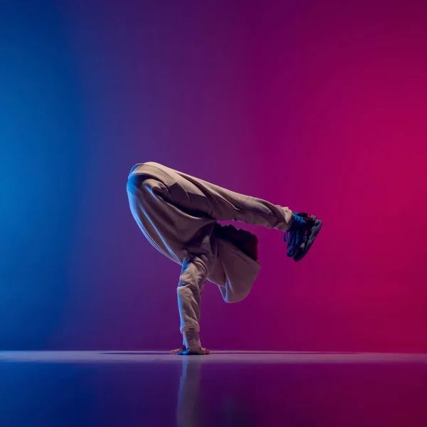 Photo studio de jeune homme sportif flexible dansant breakdance en tenue blanche sur fond rose bleu dégradé. Concept d'action, art, beauté, sport, jeunesse — Photo