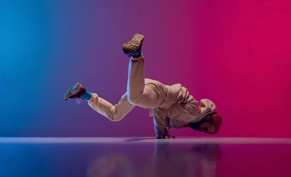 Studio shot van jonge flexibele sportieve man dansen breakdance in witte outfit op gradiënt roze blauwe achtergrond. Concept van actie, kunst, schoonheid, sport, jeugd — Stockfoto