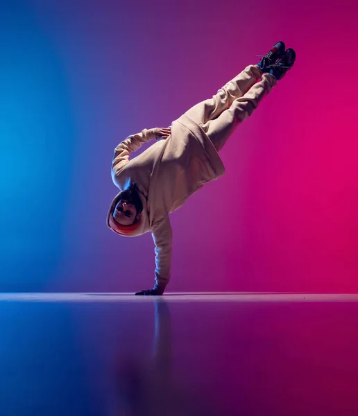 Estúdio tiro de jovem homem esportivo flexível dança breakdance em roupa branca em gradiente rosa fundo azul. Conceito de ação, arte, beleza, esporte, juventude — Fotografia de Stock
