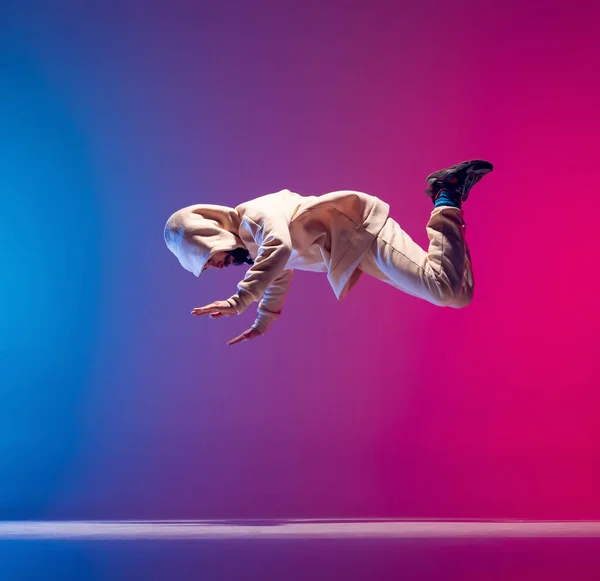 Vrije val. Studio shot van jonge flexibele sportieve man dansen breakdance in witte outfit op gradiënt roze blauwe achtergrond. Concept van actie, kunst, schoonheid, sport, jeugd — Stockfoto