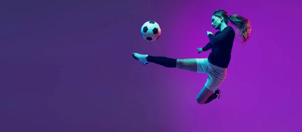 Емоційна дівчина, жіночий футбол, футболістка в русі, дії ізольовані на фіолетовому студійному фоні в неоновому світлі. Спорт, активний, здоровий спосіб життя — стокове фото