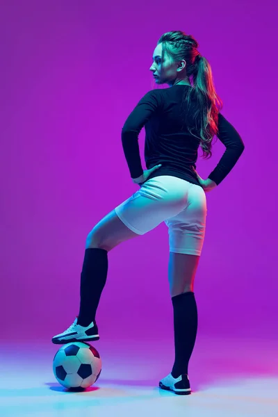 Portré gyönyörű lány, profi női focista pózol labdarúgó labda elszigetelt lila stúdió háttér neon fény. Sport, csapat, játékok, fitness — Stock Fotó