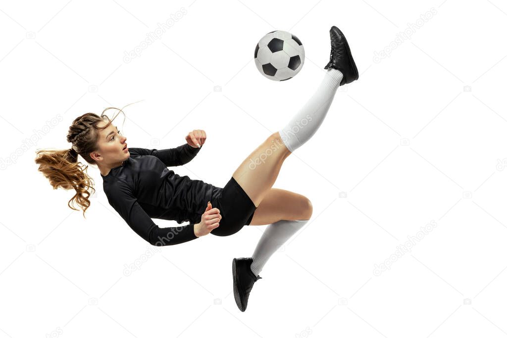 Jumping. One sportive girl, female soccer player training with football ball isolated on white studio background. Sport, action, motion, fitness