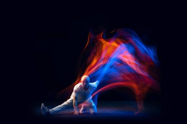 Hip-hop hareketleri. Beyaz kotlu kel bir adam ve tee dansı yapan hip-hop karışık neon ışıkta karanlık arka planda izole edilmiş. Gençlik kültürü, sokak tarzı ve moda, aksiyon.