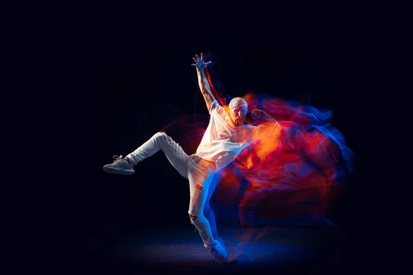Hip-hop pohyby. Plešatý muž v bílých džínách a tričko tančící hip-hop izolovaný na tmavém pozadí ve smíšeném neonovém světle. Mládež kultura, street style a móda, akce. — Stock fotografie