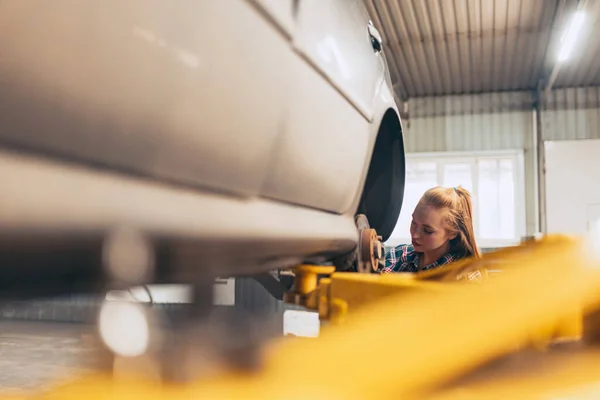 Πορτρέτο της όμορφης νεαρή κοκκινομάλλα κορίτσι, auto μηχανικός σε σταθμό αυτόματης εξυπηρέτησης χρησιμοποιώντας διαφορετικά εργαλεία εργασίας για την εξέταση του αυτοκινήτου. Ισότητα των φύλων Εργασία, επάγγελμα, αυτοκίνητο — Φωτογραφία Αρχείου