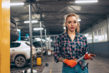 Otomobil servis istasyonunda çalışan, kendine güvenen, iş kıyafeti giyen genç bir kızın portresi. Cinsiyet eşitliği. Duygular, iş, meslek, moda, iş ve hobi