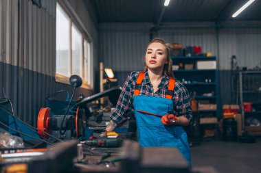 Otomobil servis istasyonunda çalışan, kendine güvenen, iş kıyafeti giyen genç bir kızın portresi. Cinsiyet eşitliği. Duygular, iş, meslek, moda, iş ve hobi