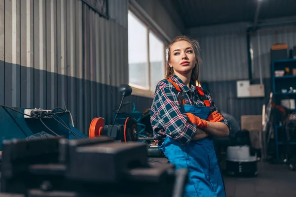 Retrato de una joven confiada con ropa de trabajo de pie en la estación de servicio de automóviles, en el interior. Igualdad de género. Emociones, trabajo, ocupación, moda, trabajo y hobby —  Fotos de Stock