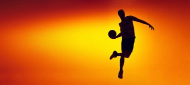Hareket halindeki basketbol oyuncusunun silueti, neon ışıklarıyla izole edilmiş sarı turuncu arka planda hareket. Spor, çeşitlilik, aktivite kavramları. El ilanı