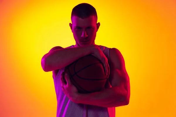 Studio záběr svalnatého muže, basketbalista, Danker izolovaný na svahu žluté purpurové pozadí v neonovém světle. Krása, sport, pohyb, pojetí aktivity. — Stock fotografie