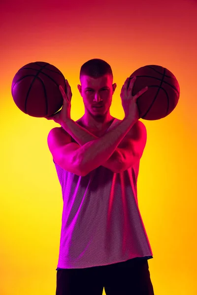 Estudio de tiro de hombre musculoso, jugador de baloncesto, danker aislado en degradado amarillo púrpura fondo en luz de neón. Belleza, deporte, movimiento, conceptos de actividad. — Foto de Stock
