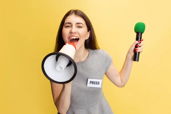 Портрет молодої дівчини, кореспондентський крик на мегафоні ізольований на жовтому студійному фоні. Концепція соціальних мереж, преси, новин, інформації — стокове фото