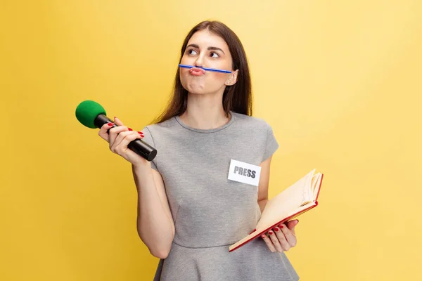 Портрет молодої дівчини, кореспондент, який тримає мікрофон репортера ізольований на жовтому студійному фоні. Концепція соціальних мереж, преси, новин, інформації — стокове фото