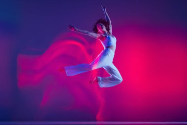 Genç sportif güzel kız, hip-hop dansçısı hip hop dansçısı pembe neon ışıkta mor arka planda izole edilmiş. Gençlik kültürü, tarz ve moda, aksiyon.