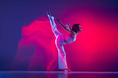 Genç sportif güzel kız, hip-hop dansçısı hip hop dansçısı pembe neon ışıkta mor arka planda izole edilmiş. Gençlik kültürü, tarz ve moda, aksiyon.