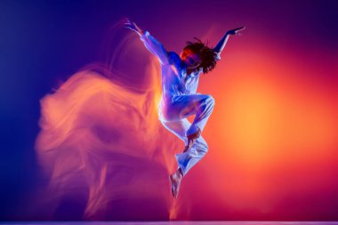 Esnek genç kız görüntüsü, beyaz kıyafetli hip-hop dansçısı, mavi arka planda izole edilmiş hip hop dansı yapan sarı neon ışığı. Gençlik kültürü, tarz ve moda, aksiyon.