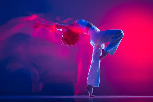 ピンクのネオンの光の中で紫色の背景に隔離された若いスポーツの美しい少女、ヒップホップダンサーのダンスヒップホップ。若者文化、スタイル、ファッション、アクション. — ストック写真