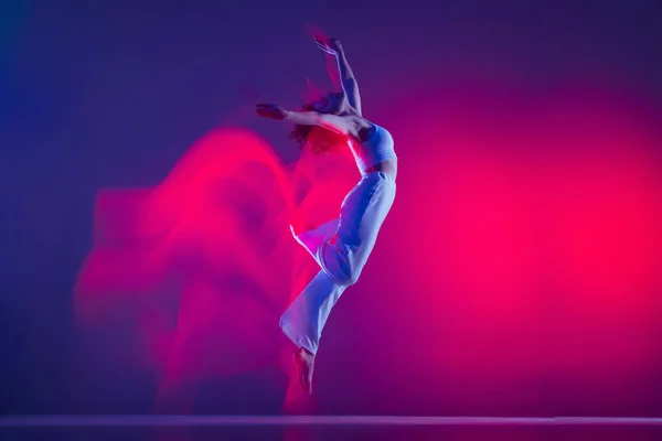 Let. Mladá sportovní krásná dívka, hip-hop tanečník tanec hip hop izolované na fialovém pozadí v růžovém neonovém světle. Mládež kultura, styl a móda, akce. — Stock fotografie