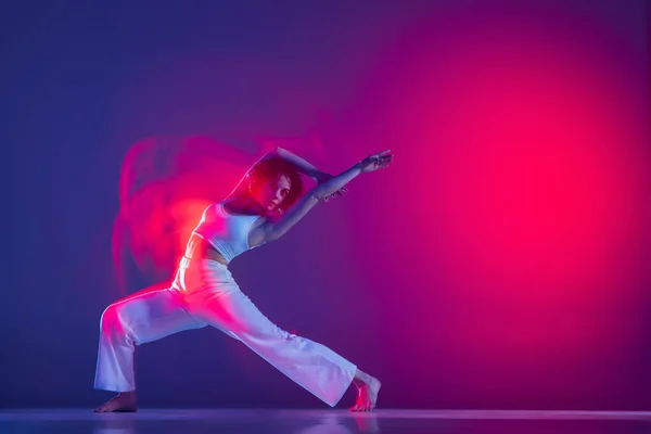 年轻而活泼美丽的女孩，嘻哈舞者在粉色霓虹灯的紫色背景下跳嘻哈。青年文化、风格和时尚、行动. — 图库照片