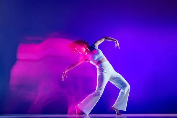 Dynamický portrét krásné dívky, hip-hop tanečnice v bílém kostýmu tanec hip hop izolované na modrém pozadí v růžovém neonovém světle. Mládež kultura, styl a móda, akce. — Stock fotografie