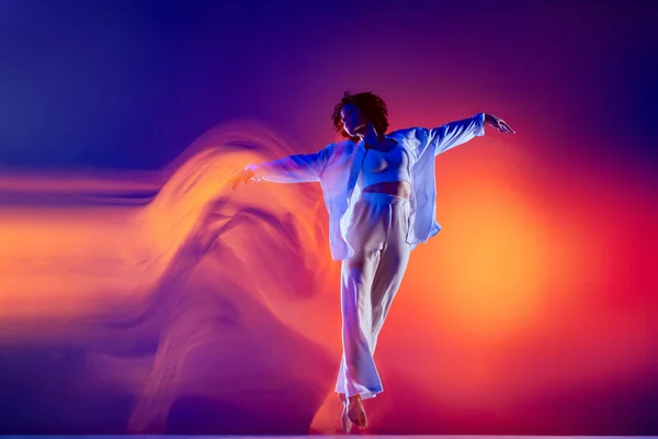 Imagem de menina flexível, dançarina de hip-hop em roupa branca dançando hip hop isolado em fundo azul em luz de néon amarelo. Cultura juvenil, estilo e moda, ação. — Fotografia de Stock