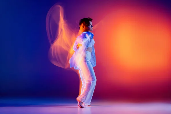 Desporto e beleza. Imagem de menina flexível, dançarina de hip-hop em roupa branca dançando hip hop isolado em fundo azul em luz de néon amarelo. — Fotografia de Stock