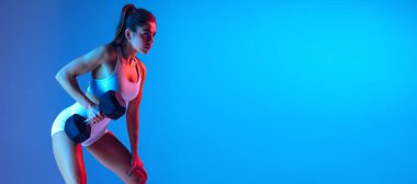 Dayanıklılık eğitimi. Spor ekipmanlarıyla genç sportif kız eğitimi neon ışıklarıyla izole edilmiş mavi-pembe stüdyo arka planında. Spor, eylem, fitness, gençlik konsepti.