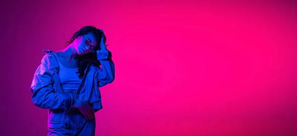 Volador. Hermosa chica joven emocional, estudiante con el pelo largo y oscuro aislado en el fondo de color rosa-azul degradado en luz de neón. Concepto de emociones, juventud —  Fotos de Stock