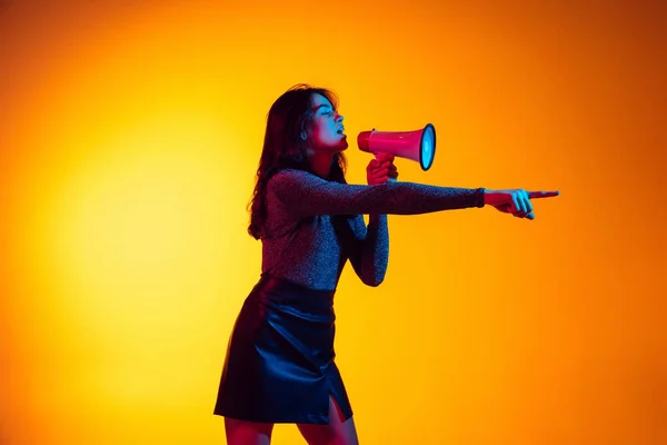 Hermosa chica excitada joven, estudiante con el pelo largo y oscuro aislado en el fondo amarillo degradado en luz de neón. Concepto de emociones, juventud — Foto de Stock