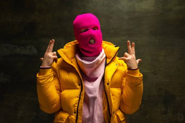 Pembe kar maskeli, sarı ceketli, koyu renk bir ceketi olan isimsiz bir adamın stüdyo fotoğrafı. Güvenlik, sanat, moda kavramı