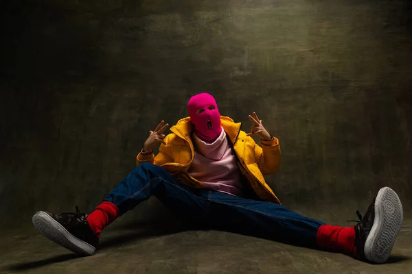 Stúdió felvétel fiatal névtelen férfi rózsaszín maszk és sárga le kabát, kabát elszigetelt sötét vintage háttér. A biztonság, a művészet és a divat fogalma — Stock Fotó
