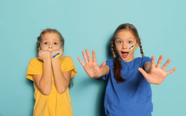 Korkmuş küçük kızların kavramsal portresi, mavi arka planda izole bir şekilde bağıran çocuklar. Ukrayna 'da barış kavramı, savaş yok, çocukları kurtarmak