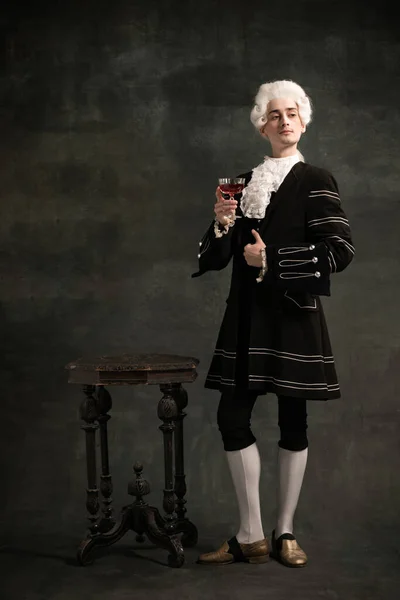 Jongeman in beeld van Amadeus Mozart, middeleeuws persoon geïsoleerd op donkergroene vintage achtergrond. Retro stijl, vergelijking van tijdperken concept. — Stockfoto