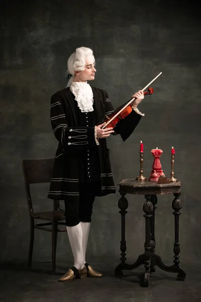 Junger Mann im Bild von Amadeus Mozart, mittelalterliche Person isoliert auf dunkelgrünem Vintage-Hintergrund. Retro-Stil, Vergleich des Epochenkonzepts. — Stockfoto