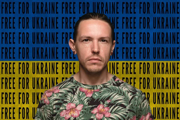 Портрет кавказького чоловіка, який плаче за Україною і мир ізольований над синім і жовтим прапором з написом "Free for Ukraine". — стокове фото