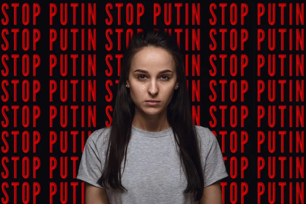 Портрет української дівчини плаче через війну, ізольовану над чорним фоном з червоним написом Stop Putin — стокове фото