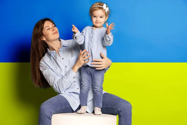 Portrait de jeune femme, mère avec sa petite fille, fille isolée sur fond bleu et jaune drapeau ukrainien. Libérer l'Ukraine — Photo