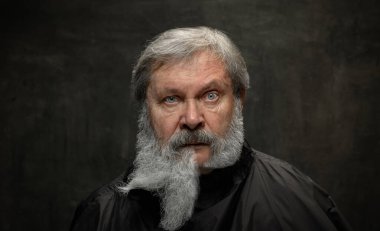 Koyu renkli arka planda izole edilmiş kameraya bakan yaşlı adamın klasik portresi. Duyguların kavramı, moda, güzellik, kendini yeniden keşfetme