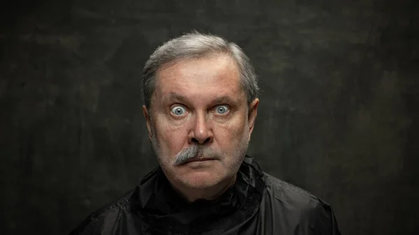 Портрет удивленного пожилого человека, смотрящего на камеру изолированного на темном винтажном фоне. Концепция эмоций, моды, красоты, самоизобретения — стоковое фото