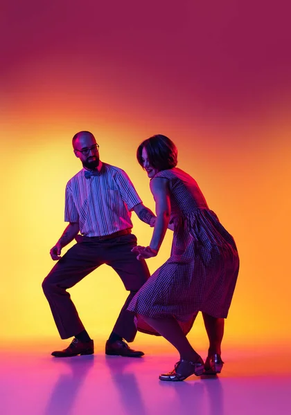 一对穿着复古风格服装的舞蹈家在深浅的黄色和紫色背景下跳着跳着林迪跳着舞，这是一对兴奋的男女的画像. — 图库照片