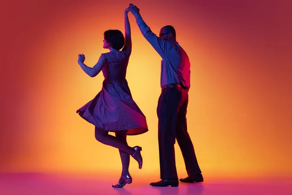 Portrét vzrušeného muže a ženy, pár tanečníků ve vintage retro stylu oblečení tanec lindy hop tanec izolované na gradient žluté a fialové pozadí. — Stock fotografie