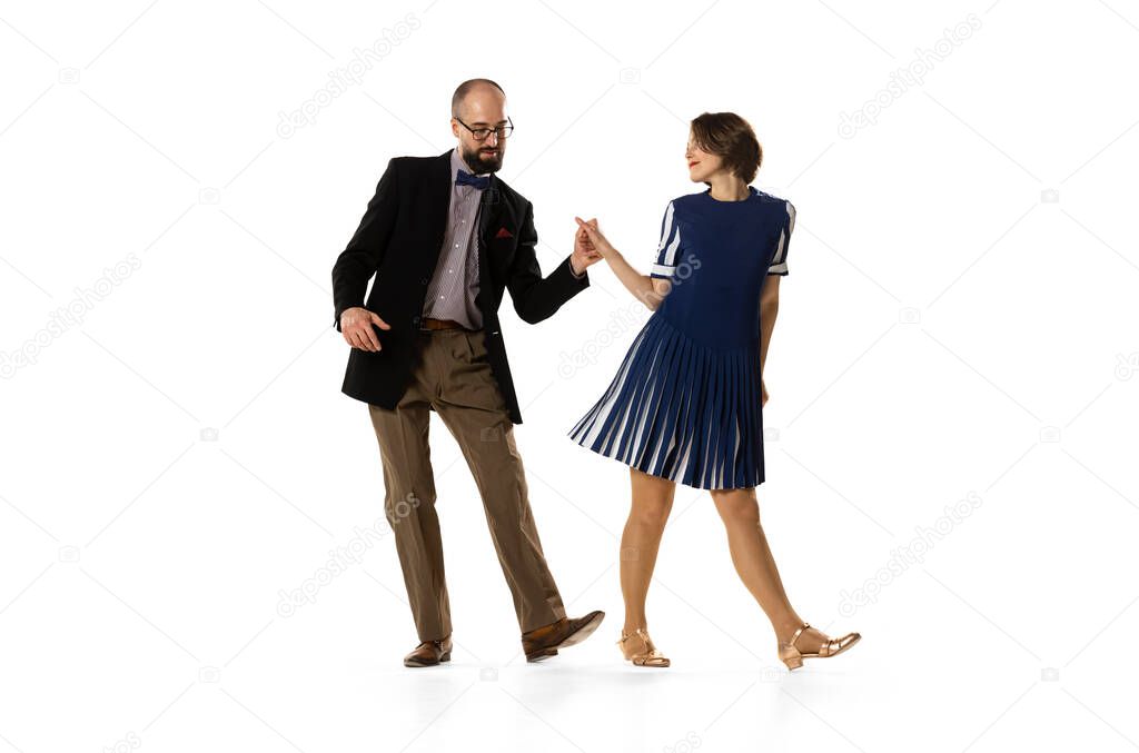 Social dancing. Couple of dancers, young man and woman in vintage retro style outfits dancing swing dance isolated on white background. Timeless traditions