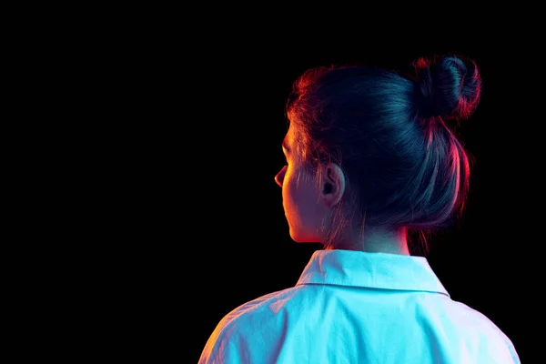 흰 셔츠 를 입은 소녀가 푸른 네온 빛 과 여과기를 사용하여 어두운 배경에 격리되어 있는 것을 뒤에서 볼 수있다. 감정, 패션, 젊음의 개념 — 스톡 사진