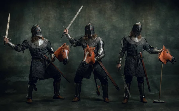 Колаж. Портрет середньовічного воїна або лицаря в шоломі та обладунках, що їздять на іграшковому коні, тримаючи великий меч ізольовано на темному тлі. Порівняння епох, історія — стокове фото