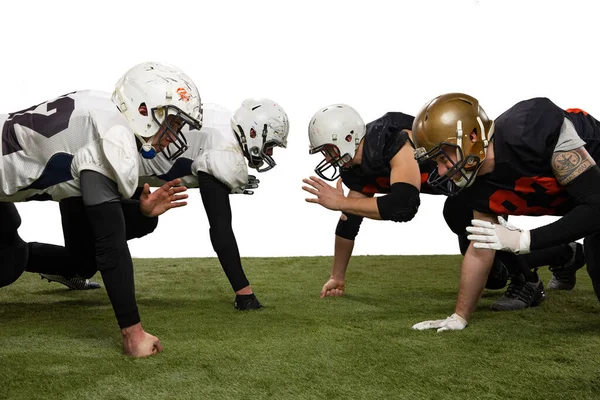 Klaar om te beginnen. Groep van jonge sportieve mannen, professionele amerikaanse voetballers in sportuniform en apparatuur poseren geïsoleerd op witte achtergrond. — Stockfoto