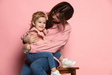 Destek ve bakım. Genç bir kadın ve küçük bir kız, anne ve kızı pembe stüdyo geçmişinde izole edilmiş. Anneler Günü kutlaması. Aile kavramı, çocukluk, annelik.